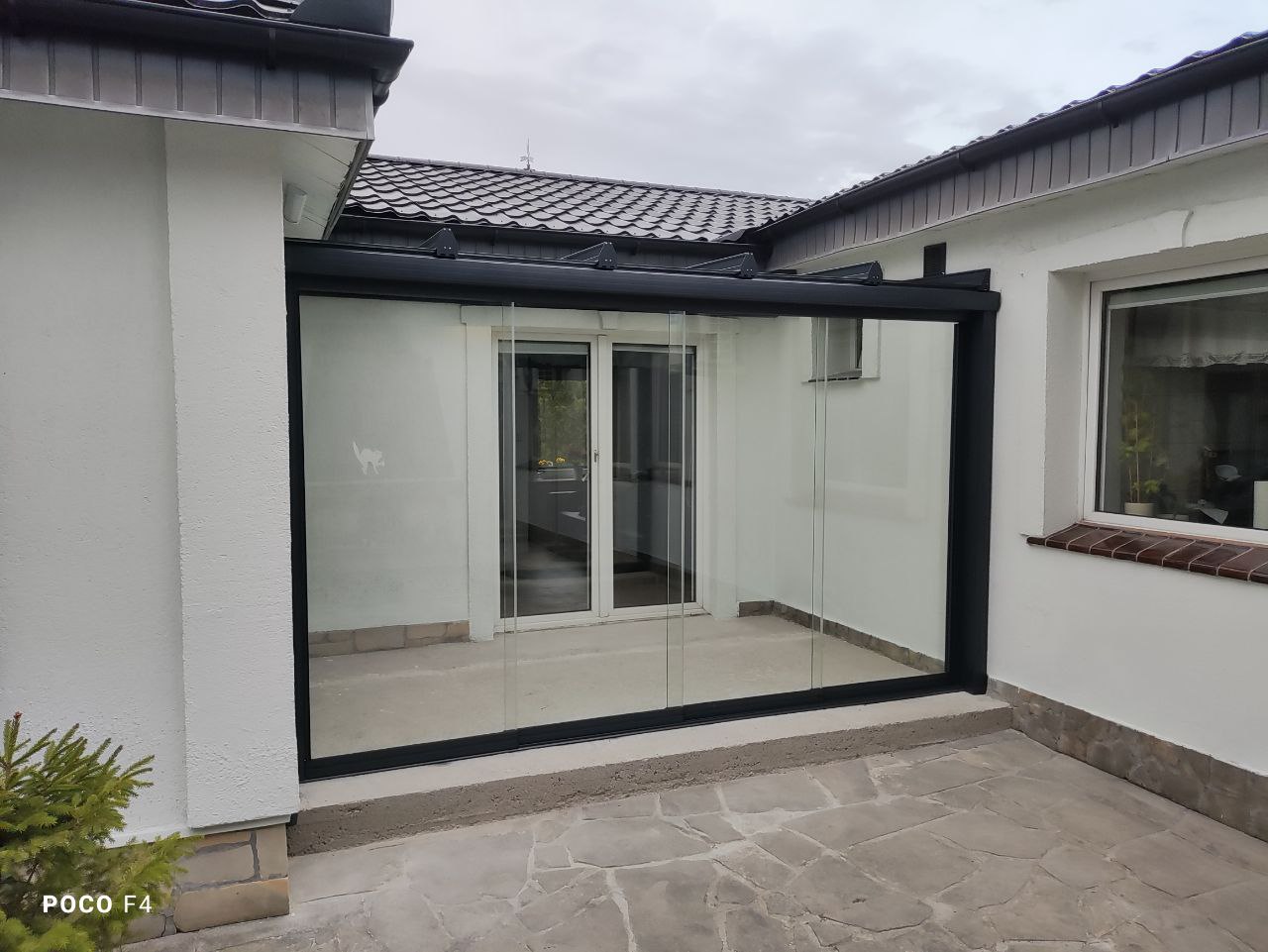 Taras we wnęce budynku z bezramową szklaną ścianą i zadaszeniem ze szkła