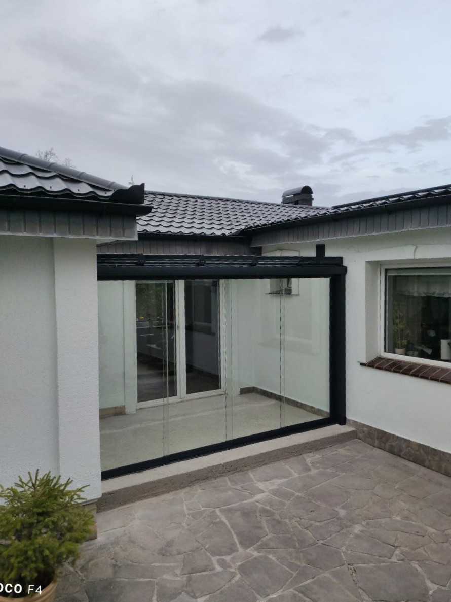 Zabudowa tarasu we wnęce budynku z nowoczesną aluminiową konstrukcją i przeszkleniem