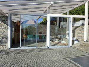 Szklane ściany przesuwne zamontowane w zadaszeniu tarasu z drewna