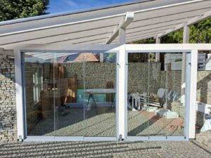 Szklane ściany przesuwne zamontowane w zadaszeniu tarasu z drewna