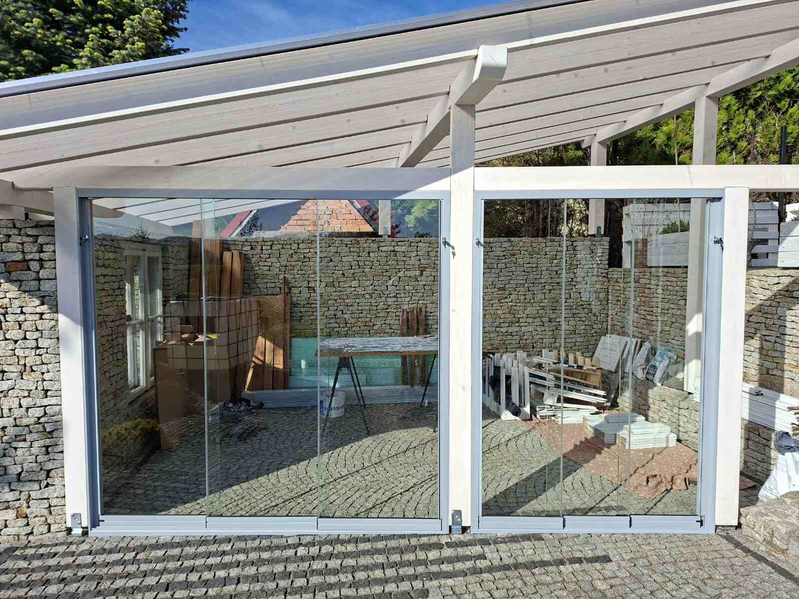 Szklane ściany przesuwne zamontowane w zadaszeniu tarasu z drewna