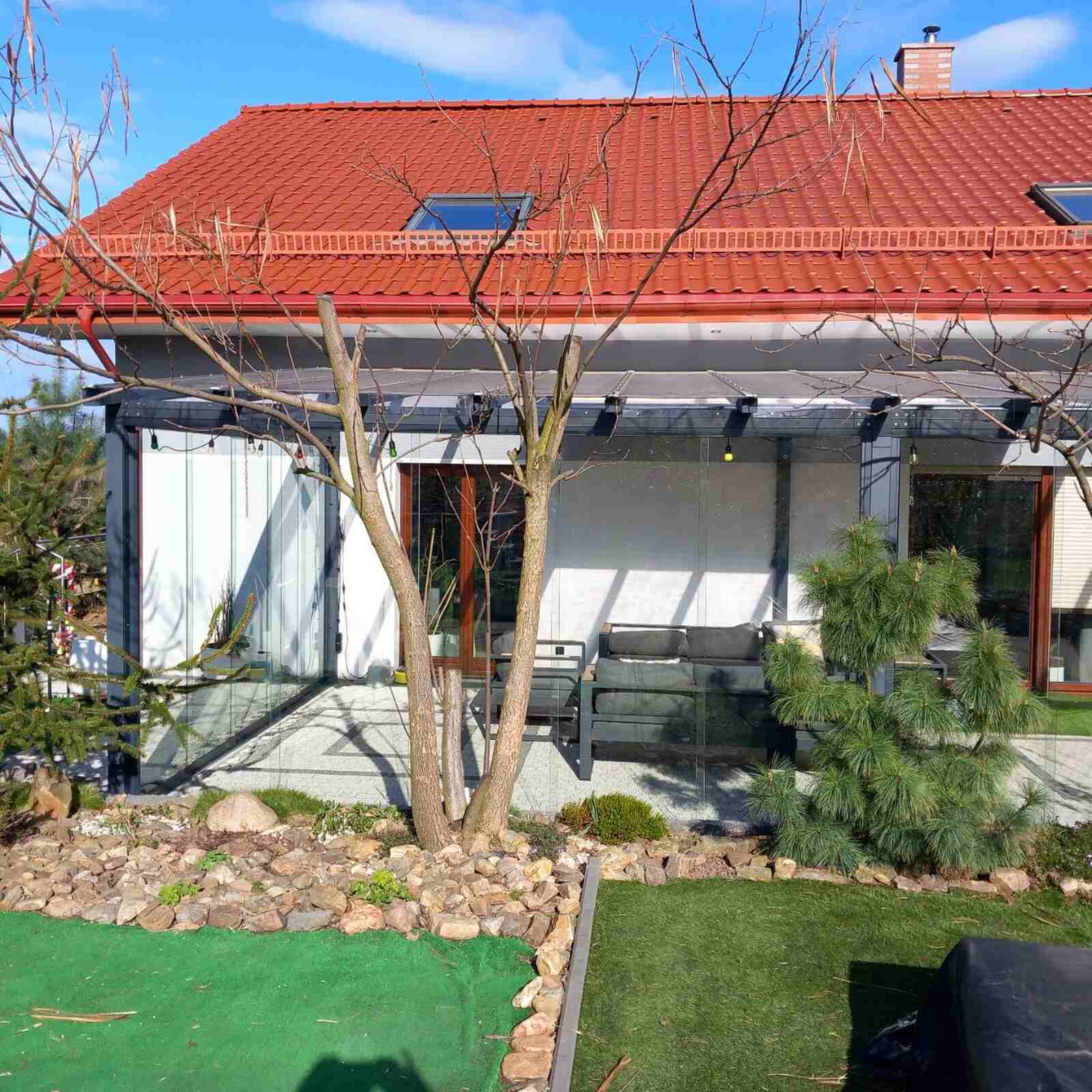 Szklana zabudowa tarasu z przesuwnymi ścianami przy nowoczesnym domu