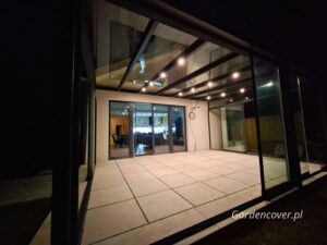 Nowoczesna zabudowa tarasu z oświetleniem nocnym i przesuwnymi szybami
