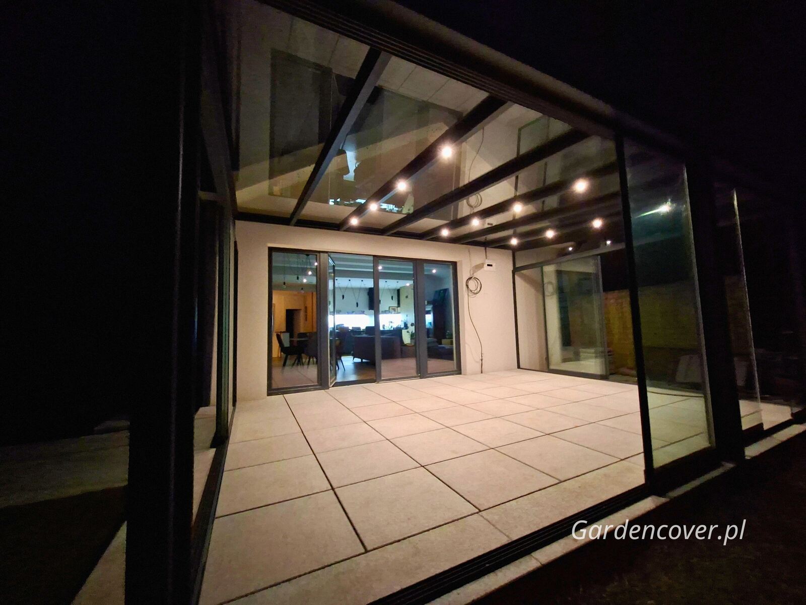 Nowoczesna zabudowa tarasu z oświetleniem nocnym i przesuwnymi szybami